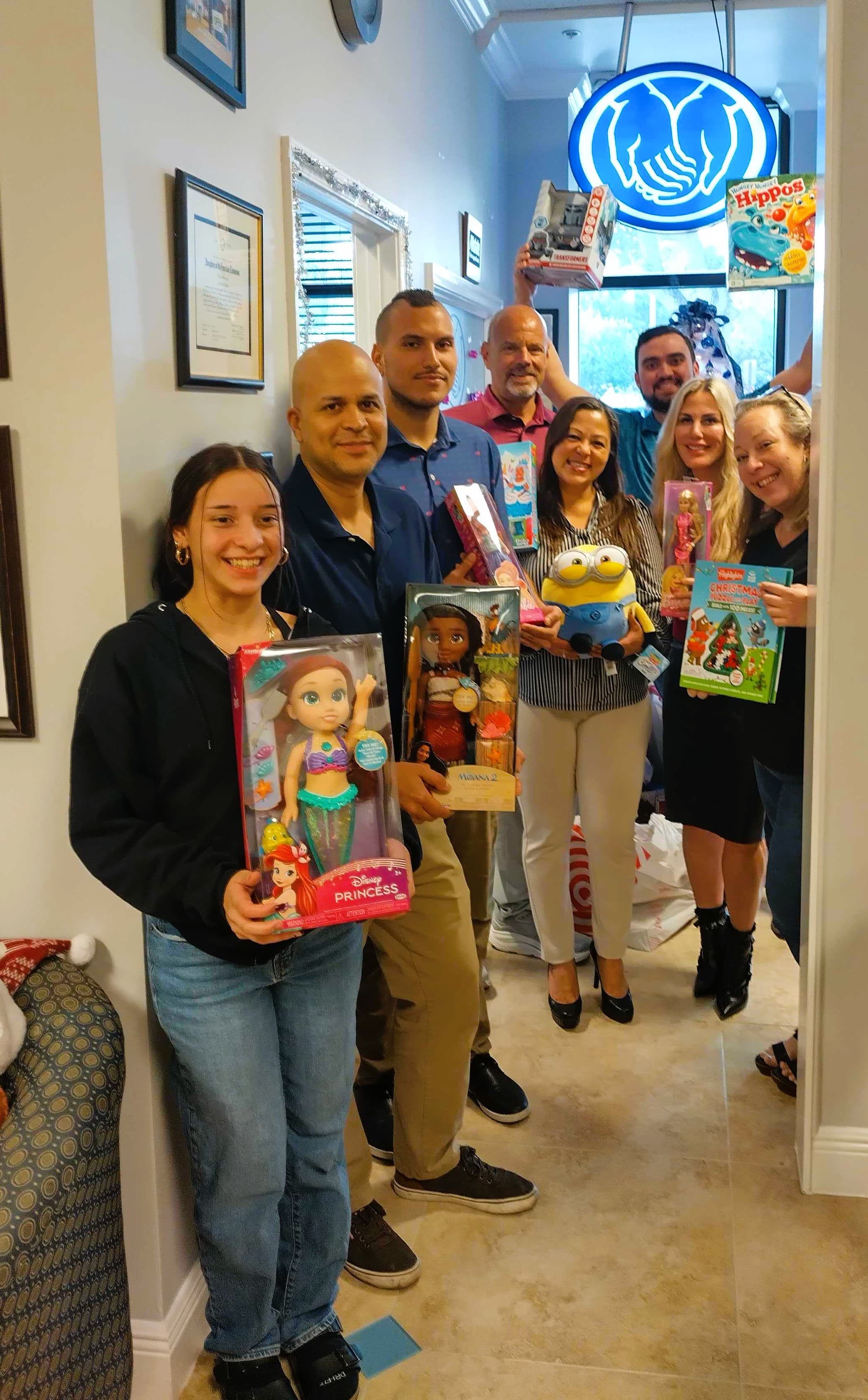 The Lisa Faina Agency team holding donated toys collected for the Women in Distress giving drive